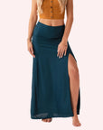 On a neutral background is a teal maxi skirt with a slit on the front side.