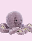 On a white background is a purple octopus stuffed animal with a smiling face.