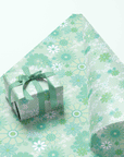 On a teal background is a gift box wrapped in a mint floral print wrapping paper with a velvet bow, not included with purchase.