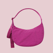 A hot pink crescent shaped shoulder bag.