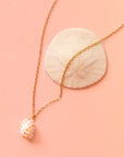 A gold chain necklace with a white spotted shell pendant.