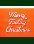 Red card that reads 'Merry Fucking Christmas' in soft pink lettering with dark red shadowing. A gold foil burst detailing beams from the text