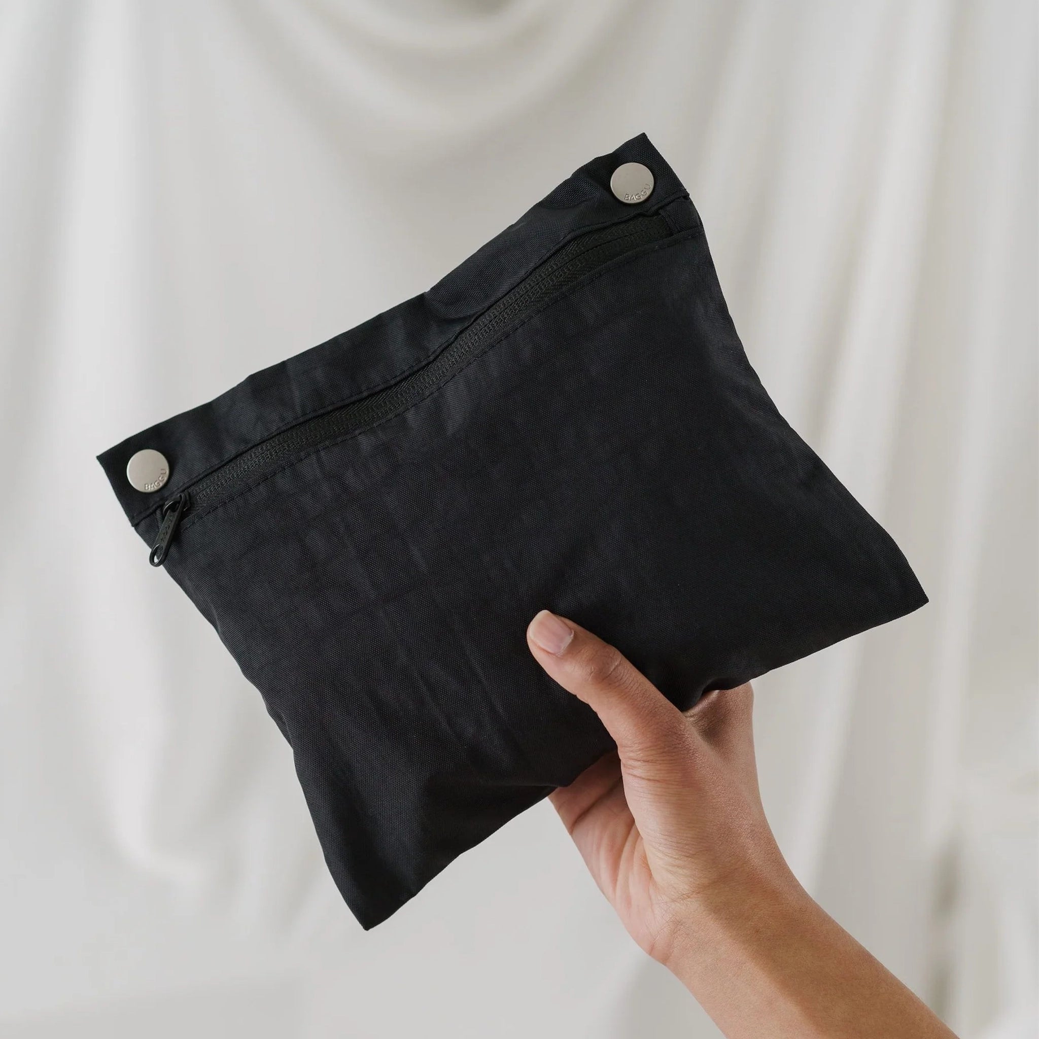 On a white background is a photograph of the black removable pouch that comes on the inside of the bag. 