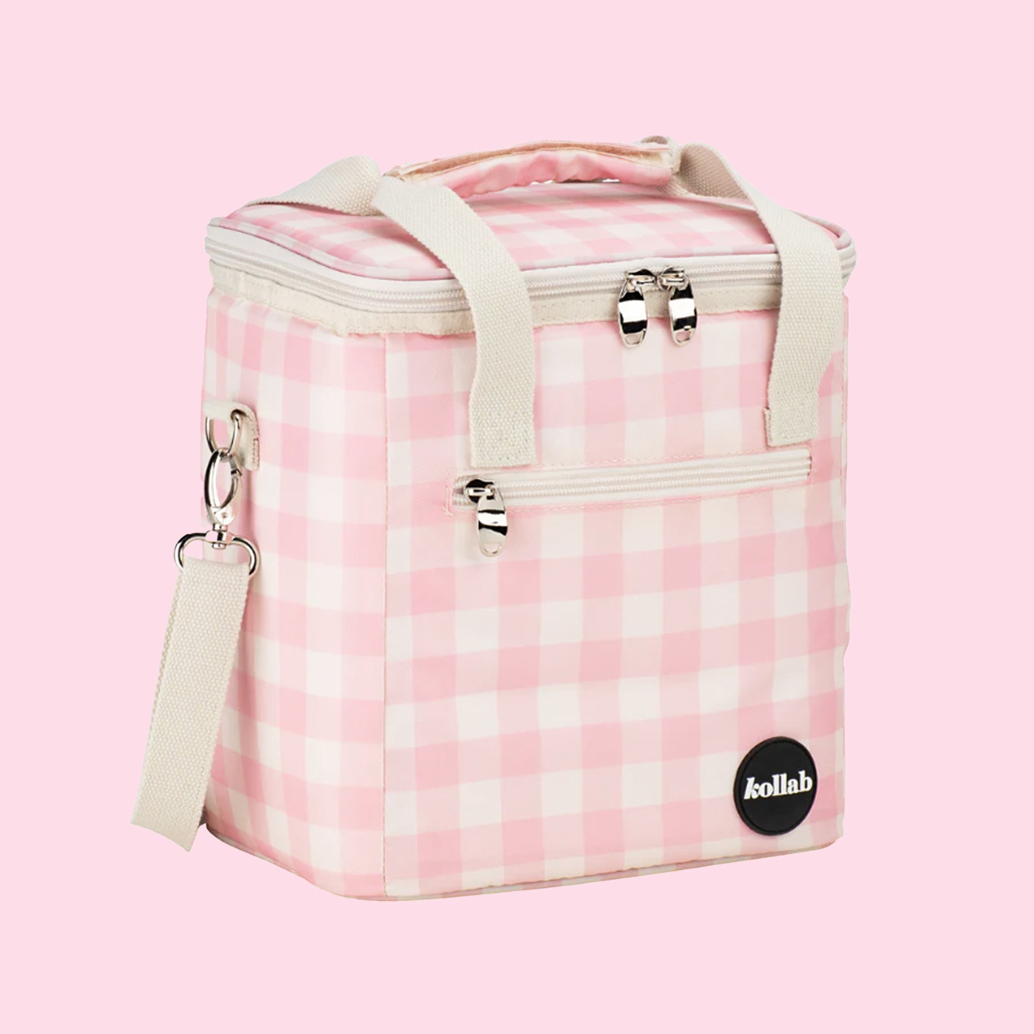 On a light pink background is a pink and white cooler bag with a long adjustable strap.