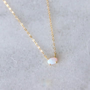 A gold necklace with an oval opal stone in the center.