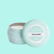 A small blue tin candle with white wax and a white diamond repeating pattern on the outside of the tin. Comes with a matching blue lid that reads, "Capri Blue Volcano".