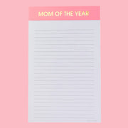 On a pink background is a lined notepad with a pink header that reads, "MOM OF THE YEAR" in gold foil letters. 