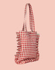 A red and white gingham printed tote bag with shoulder straps and a ruffle edge detail.