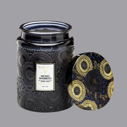 On a gray background is a decorative black glass jarred candle with a white rectangle label with the candle name "Moso Bamboo" on it.