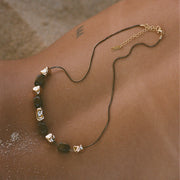 Necklace with green beads and gold accents on a person's neck