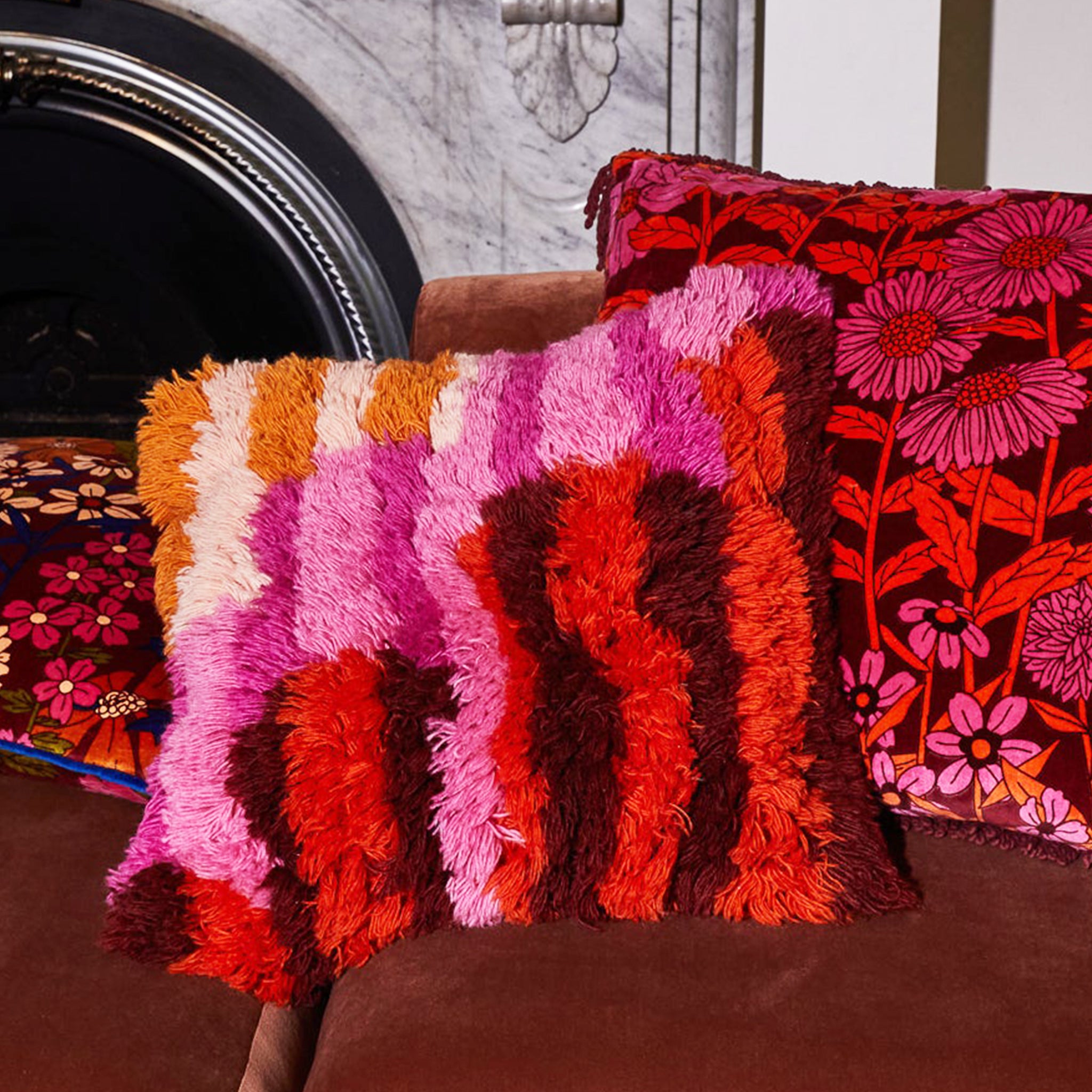 A multi colored shag pillow in orange, brown, pink and yellow shades.