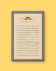 A notepad that has black and white checks as a border and black lines across the middle of the page sits on a yellow background. There is a taxi at the top of the page with the text below that reads "Don't Fuhgeddabouudit!"