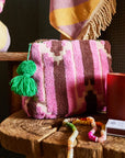The medium nisha terry pouch in pink with a green tassel zipper.