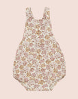 A children's romper with a light pink and yellow floral pattern.