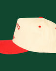 A cream and red trucker hat with embroidered text that reads, "North Pole Social Club".