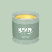 A green tin candle with white text that reads, 'Olympic Pacific Moss'.