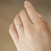 A gold band ring with an oval opal stone in the center.