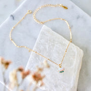 A gold chain necklace with an opal stone pendant with three small turquoise stone underneath.