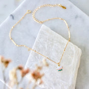 A gold chain necklace with an opal stone pendant with three small turquoise stone underneath.