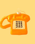 A touch tone phone ornament in a shiny orange color on a bright orange background.