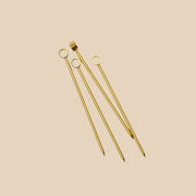 A set of four gold cocktail picks.
