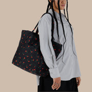 A black nylon tote bag with a red and green flower pattern.
