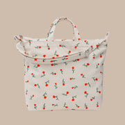 A cream colored canvas tote bag with a red and green flower pattern.