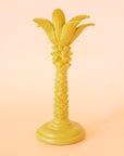 A yellow colored palm tree shaped taper candle holder.