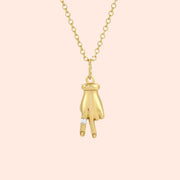 A gold necklace with a hand shaped pendant in the shape of a peace sign.