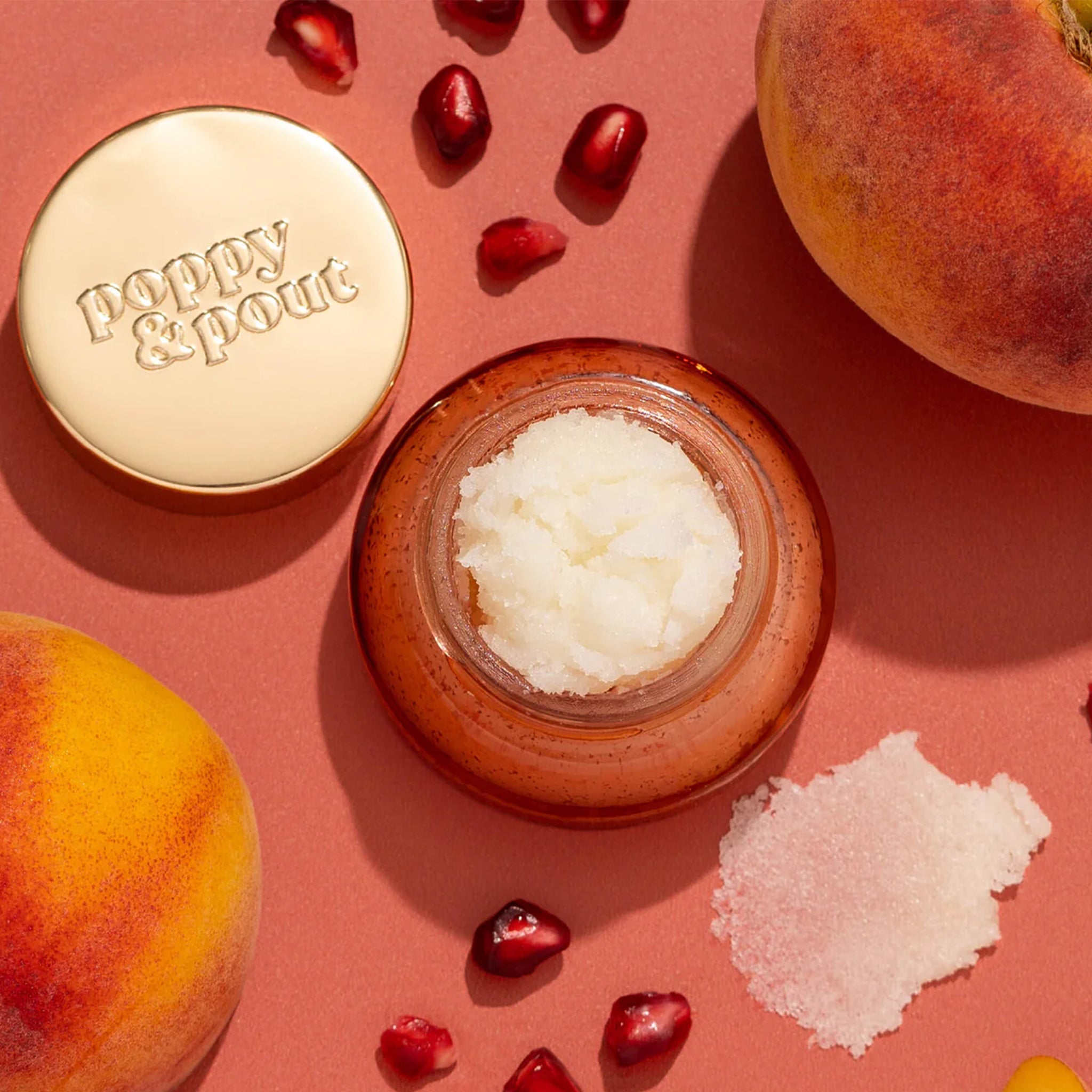 Lip scrub in an orange red container with a gold lid. This lip scrub is grainy, hydrating and perfect for your lips.