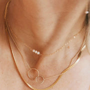 A gold chain necklace with three small pearl connected in the center.