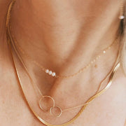 A gold chain necklace with three small pearl connected in the center.