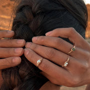 The gold hand crafted statement ring with three small pearls in the center worn on a models middle finger in this photo.