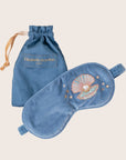 A blue velvet eye mask with an embroidered shell and pearl graphic.