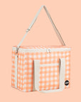 An ivory and apricot checkered print picnic bag with white straps and zippers.