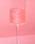 A champagne glass with a beverage inside that displays the glitter shimmer bomb's effect to the liquid.