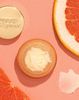 Lip scrub in a light orange colored container with a gold lid. This lip scrub is grainy, hydrating and perfect for your lips.
