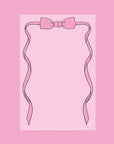 A pink notepad with bow shaped graphic on the top.