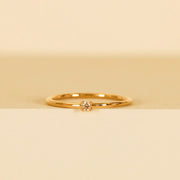A gold dainty ring with a small champagne CZ stone in the center.