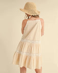 A cream tiered mini dress with spaghetti straps and lace details.