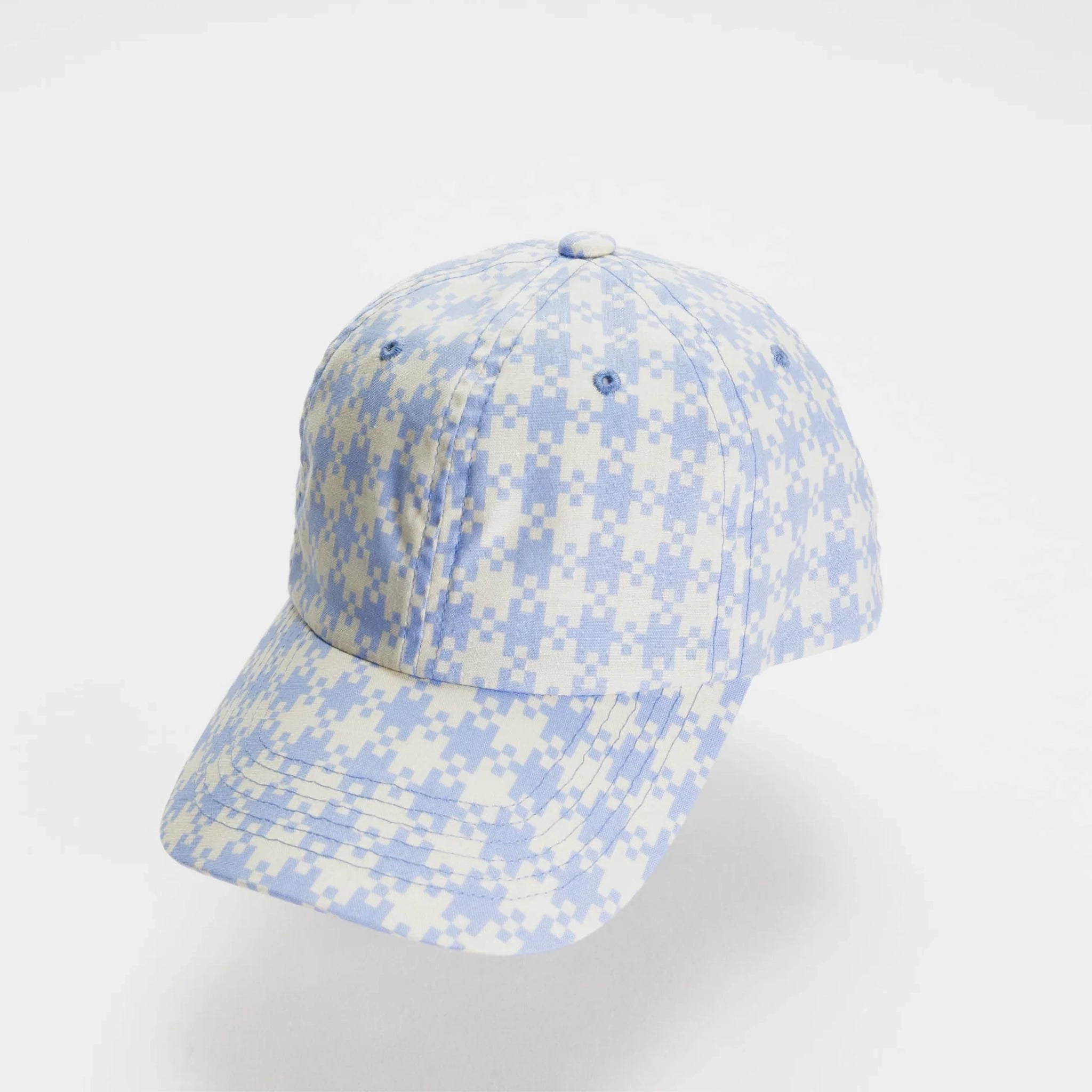 On a white background is a light blue and white gingham printed baseball hat. 