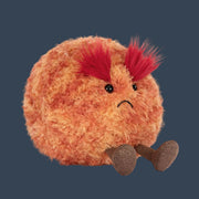 A round round orange fuzzy mars shaped stuffed toy with s frown face.