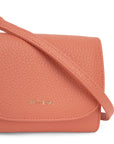 A light pinkish orange vegan leather wallet with a thin removable crossbody strap.