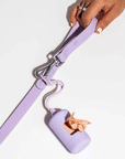 On a white background is a lavender waste bag carrier attached to a leash not included.
