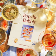 A yellow puzzle box with a photograph of a champagne tower with cherries at the bottom and text that reads, 'Piecework Puzzles'.