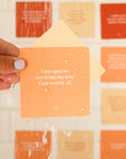 Cards with affirmations related to positivity in different shades of orange along with a shower steamer.