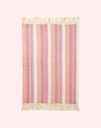 A pink and ivory striped waffle knit hand towel with tassel detailing on each end.