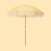 A white and yellow striped outdoor umbrella with a rope fringe detail around the edge.