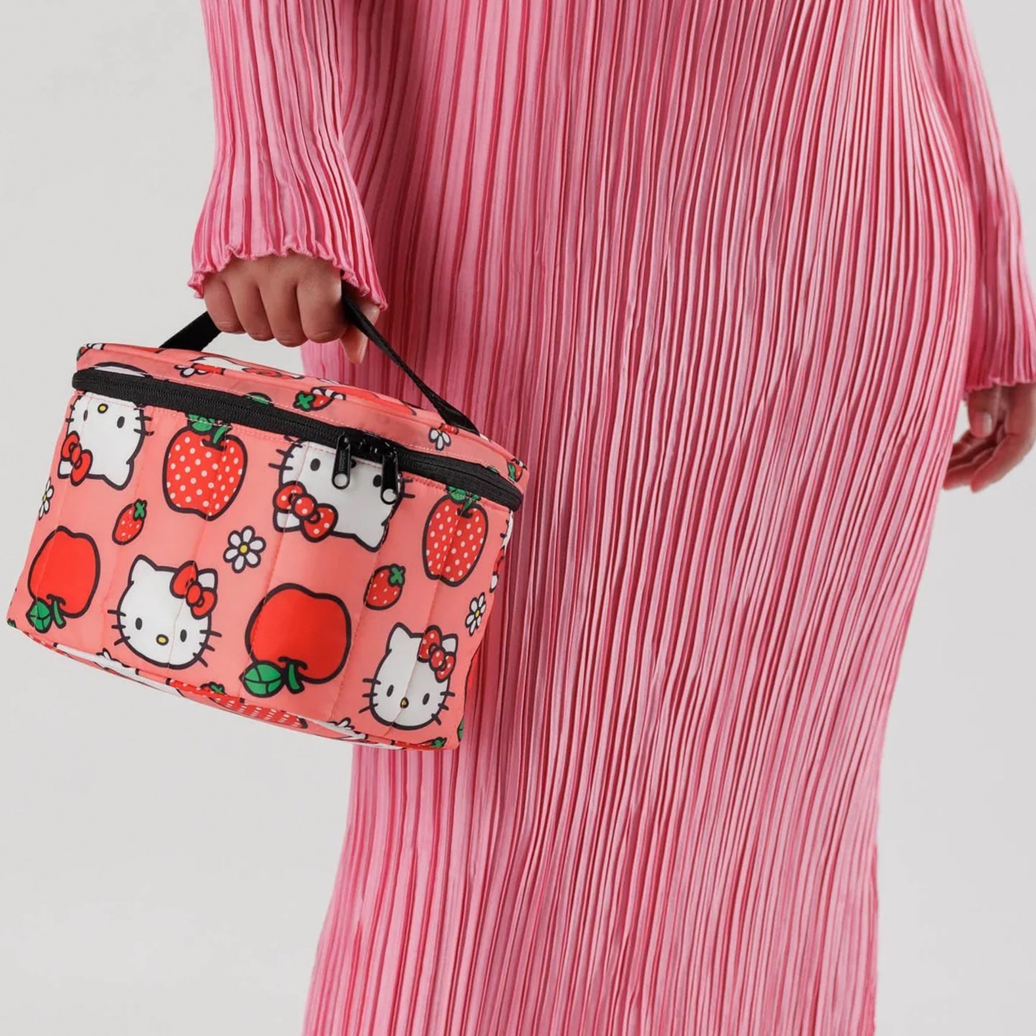 A pink and red Hellot Kitty patterned lunch box with a black handle and zipper.