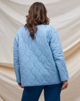 A multi colored quilted jacket with a floral print on one side and a blue solid color on the other.
